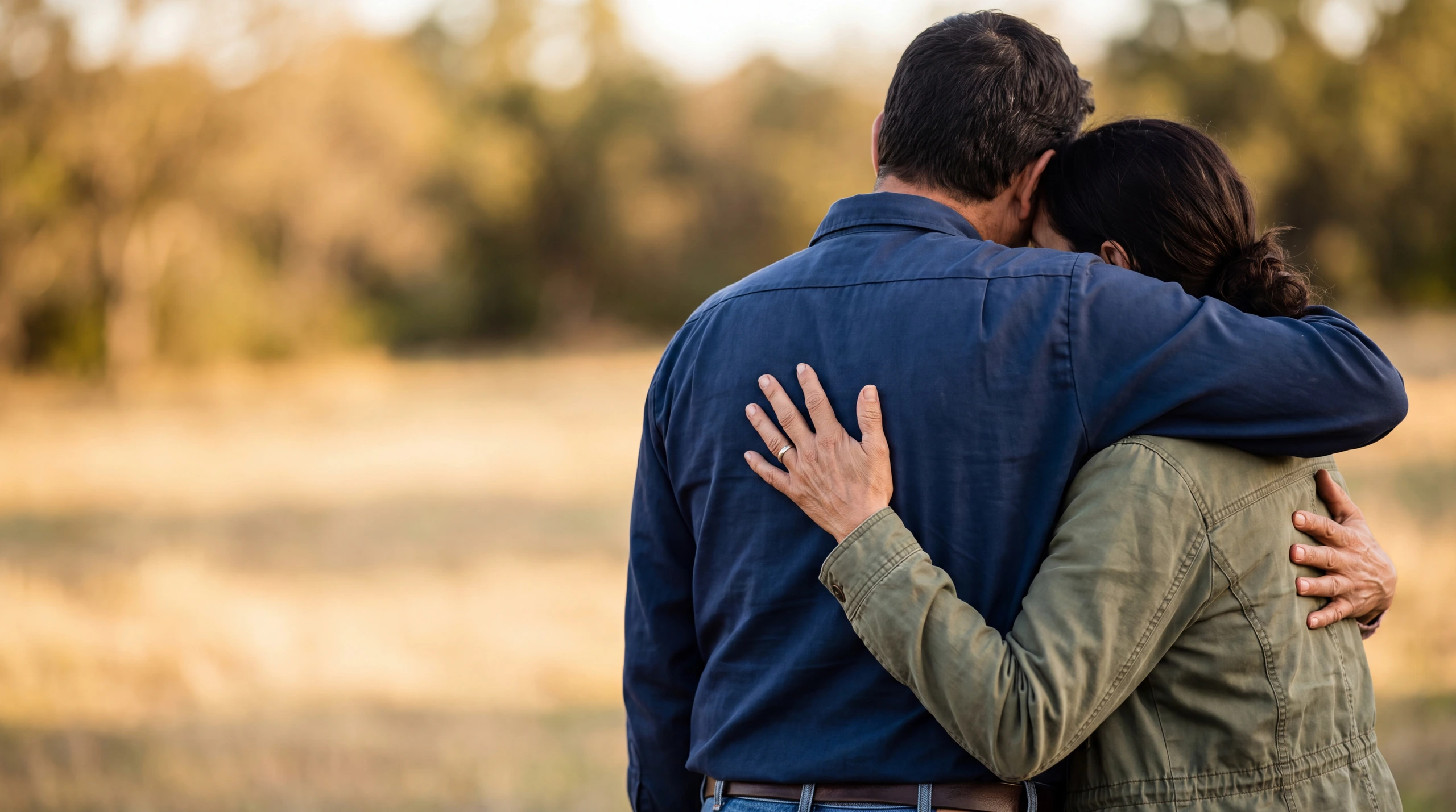 Two people holding each other in a long embrace, seen from behind