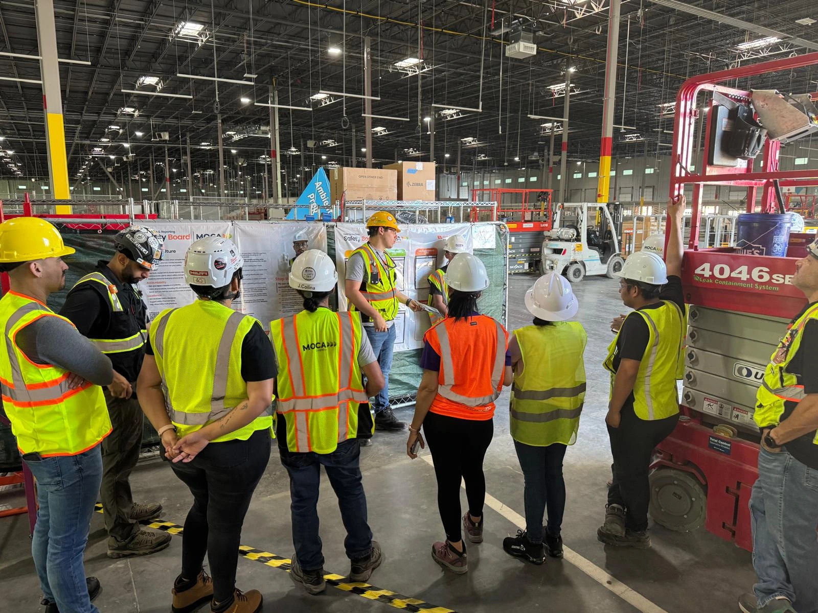 A MOCA crew in hard hats and vests gathered for a safety briefing on site